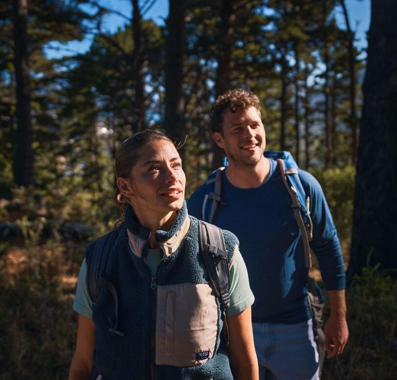 Zwei Wanderer schauen in den Wald und lächeln