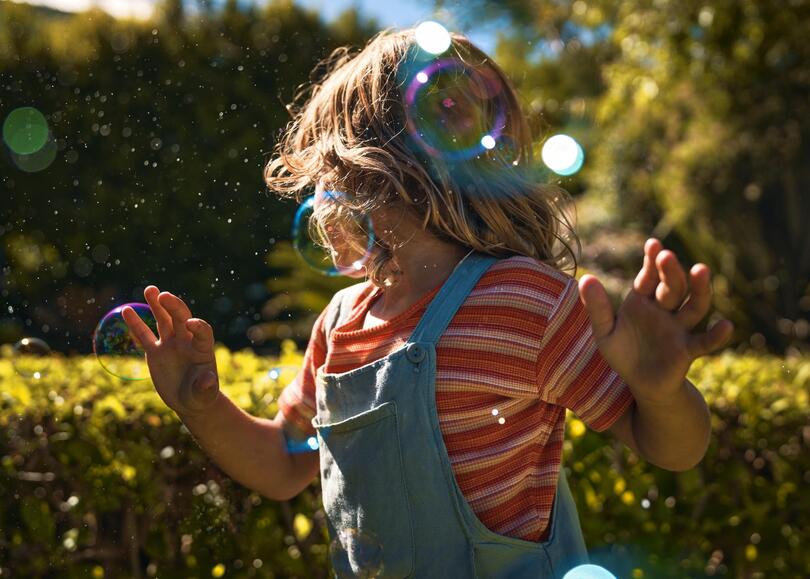 Une fille danse à l'extérieur avec des bulles de savon