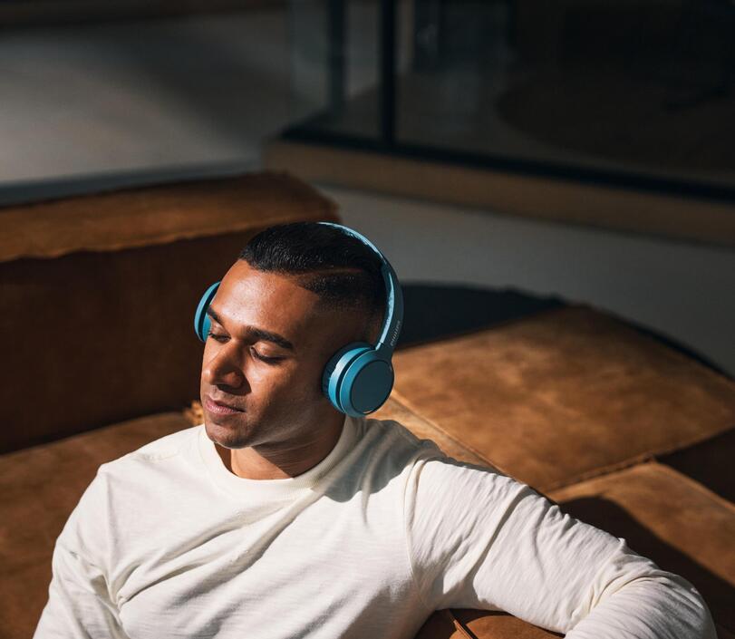 Man on a couch with headphones and eyes closed