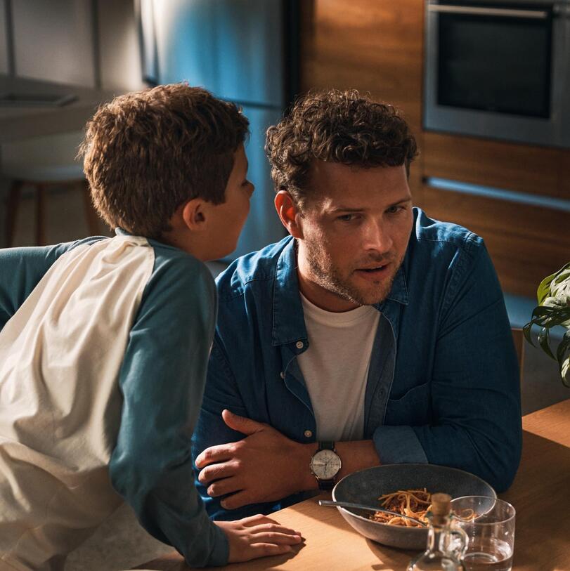 Boy whispering something in a man's ear