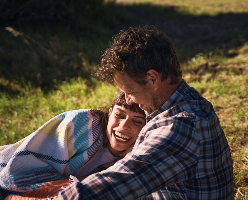 Femme et homme riant dans l'herbe